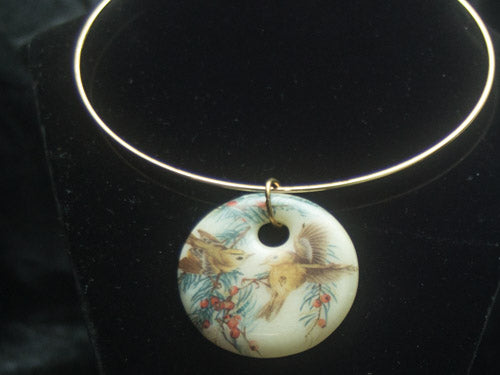 BIRDS WITH FLORAL AND TREE AQCCENTS ON OFF WHITE GLASS.. PENDANT IS HAND MADE FROM FRIT AND 2 INCHES IN DIAMETER. COMES GIFT BOCXED AND ON A GOLD COLORED WIRE CHOKER.  ONE SIZE FITS MOST